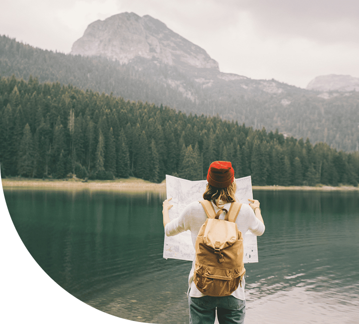 Person with backpack looking at mountain lake